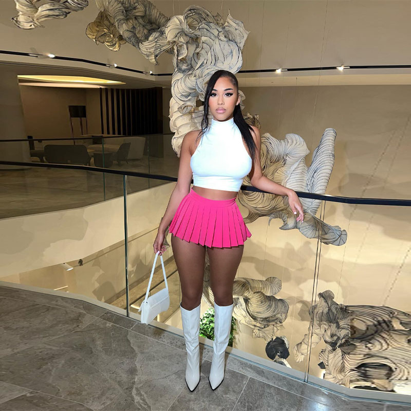 a women in a pink skirt and white top standing in front of a glass wall